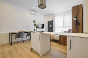 Una cocina moderna con comedor, suelo de madera y televisor instalado en la pared.