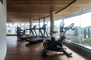 A gym with exercise equipment, large windows, and a wooden ceiling. - Luxury beachfront house at Praia do Marceneiro in Milagres (Praia do Marceneiro - Milagres)