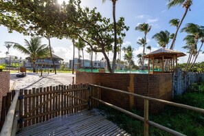 A wooden bridge leading to a beach area with palm trees and a gazebo. - Luxury beachfront house at Praia do Marceneiro in Milagres (Praia do Marceneiro - Milagres)