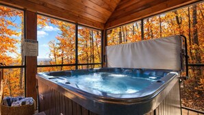Un bain à remous dans un chalet en bois, avec vue sur les arbres aux couleurs automnales.