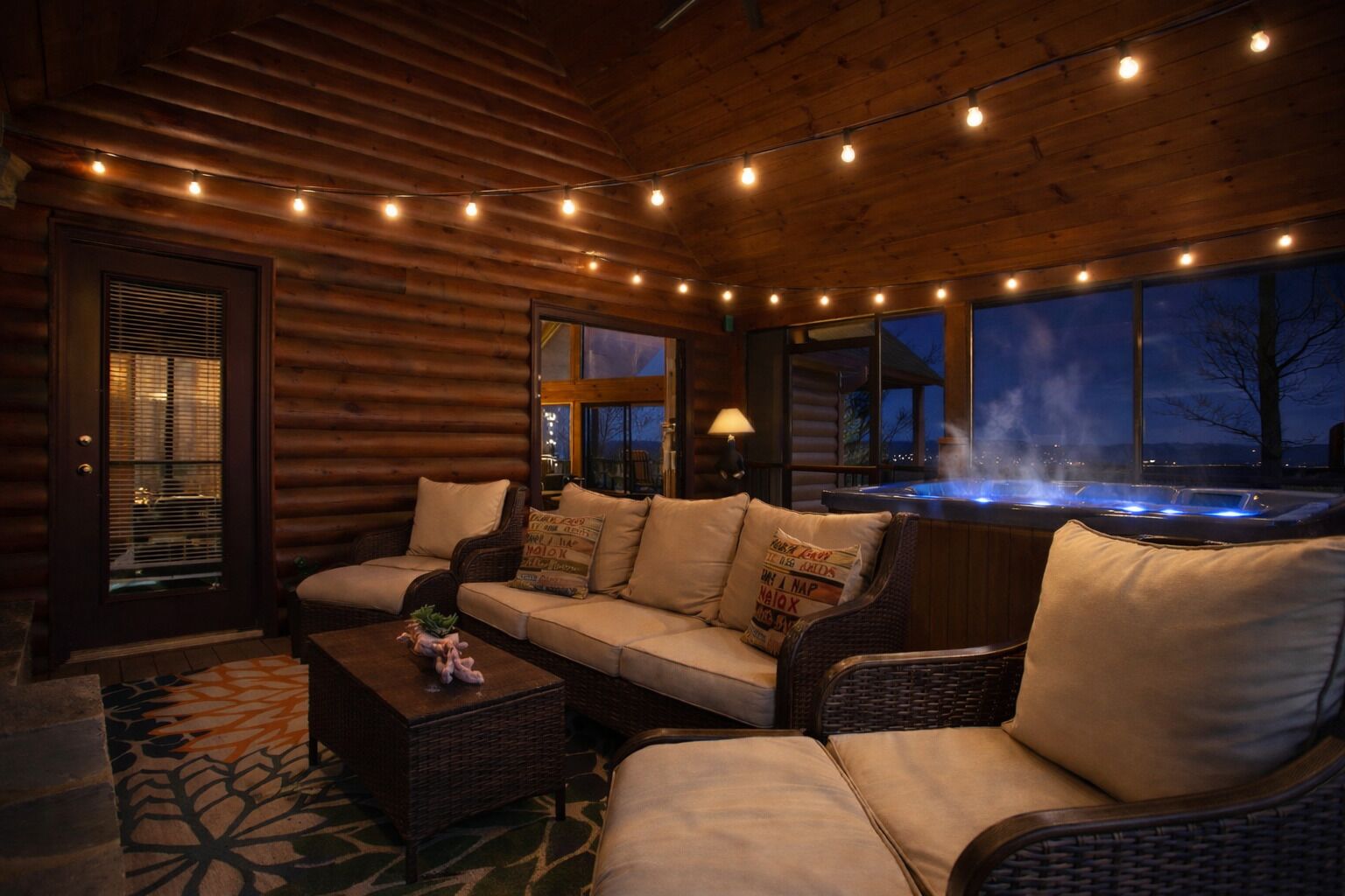 A cozy log cabin interior with a sofa, chairs, a table, and a hot tub.
