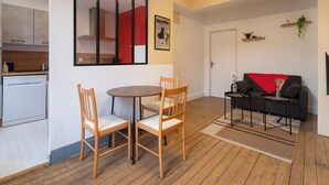 En kompakt opholdsstue med spiseplads, køkken og siddeområde.