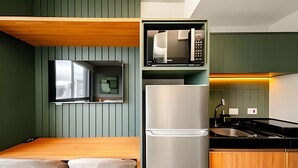 Een moderne keuken met een ingebouwde magnetron, een roestvrijstalen koelkast en een houten eettafel met twee stoelen.