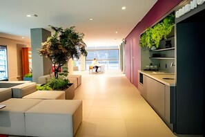 A modern hotel lobby with a seating area, a large indoor plant, and a view of the city. - DOMINGO DE MORAES  1007 (São Paulo)