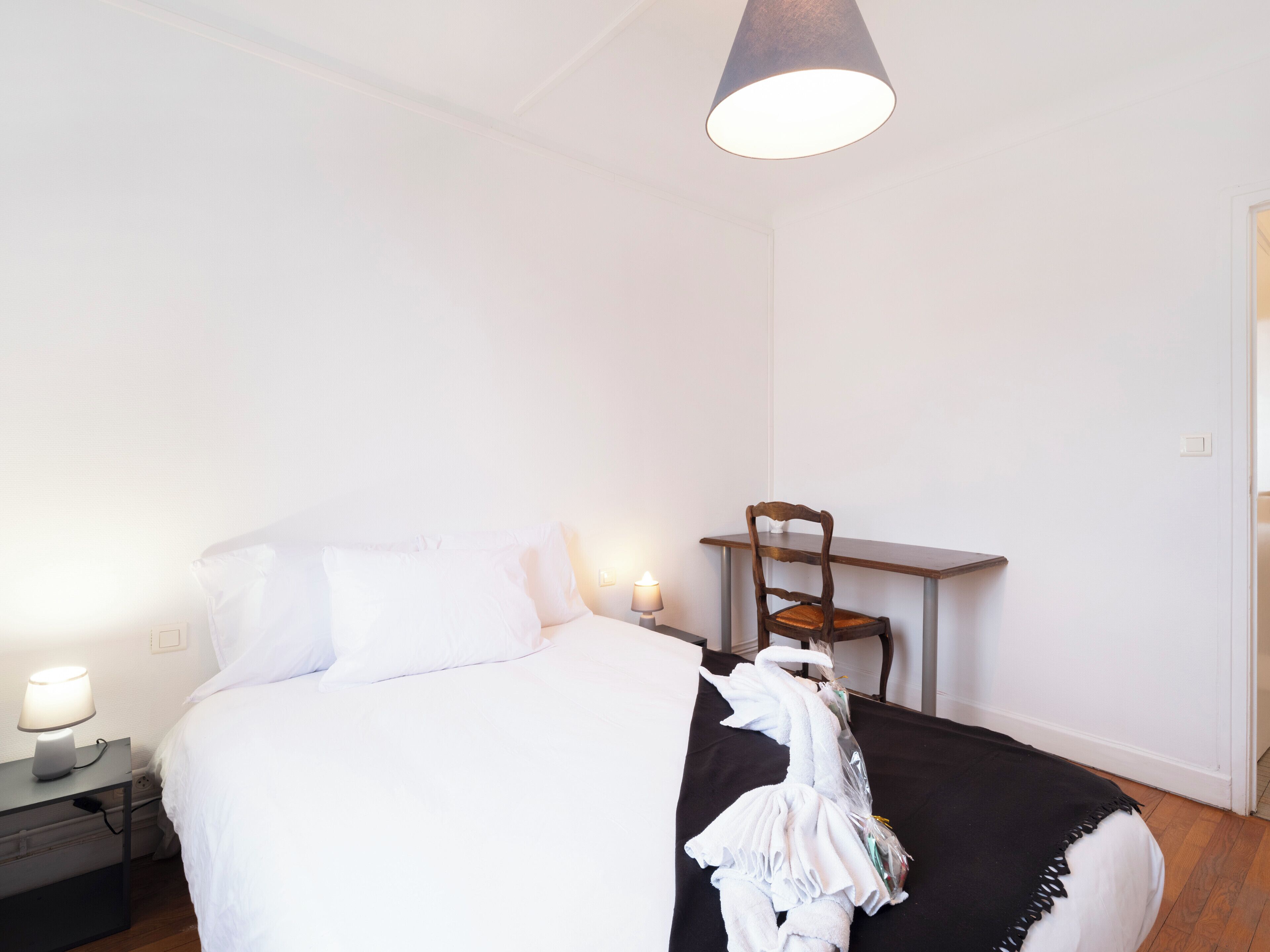 Une chambre à coucher avec un lit, une table de chevet avec une lampe, une chaise et une serviette suspendue.