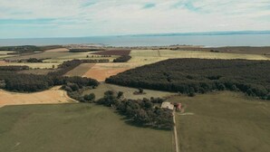 An aerial view of a rural landscape with fields, forests, and a small building.