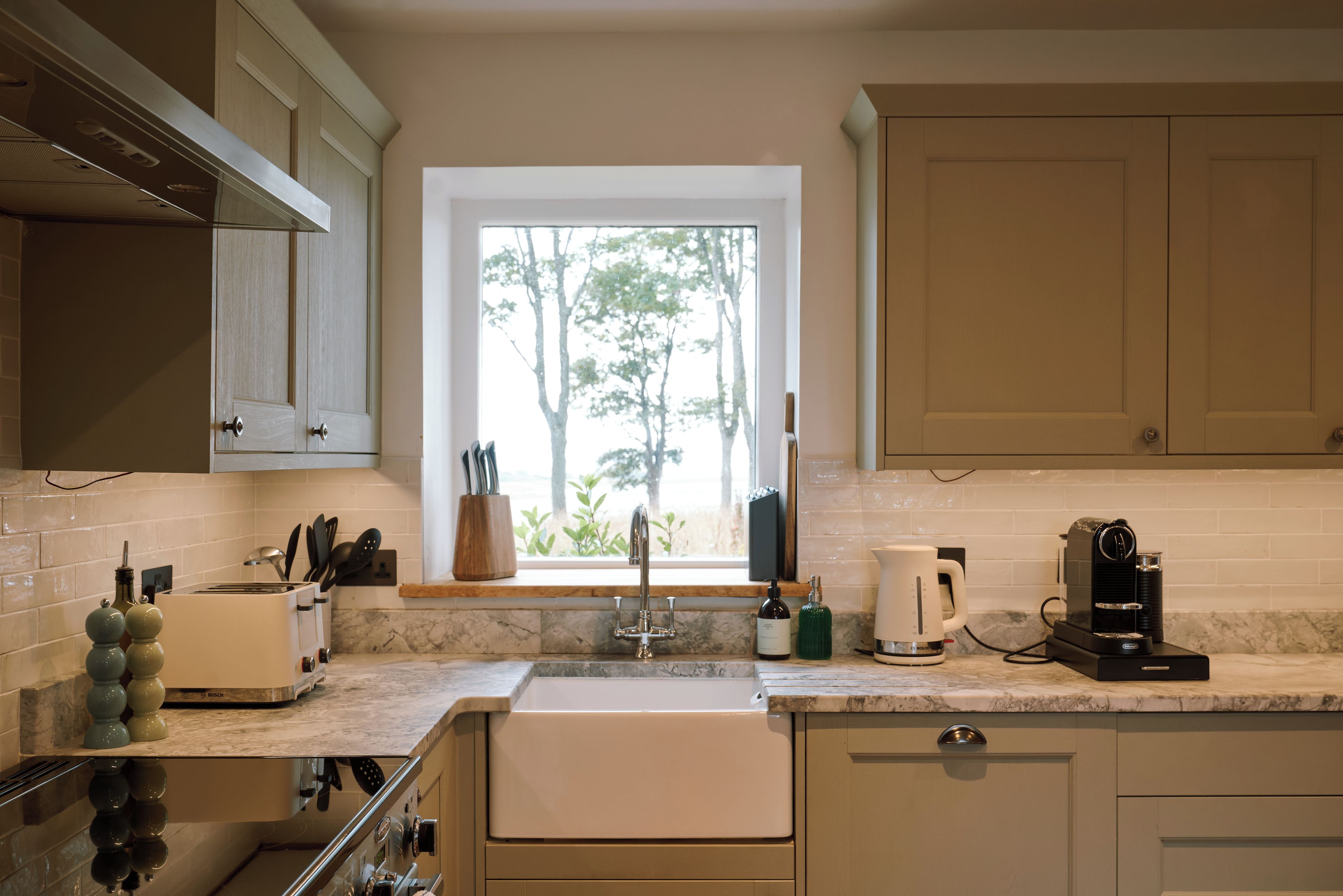 Una cucina moderna con forno a incasso, lavello e finestra vista alberi.