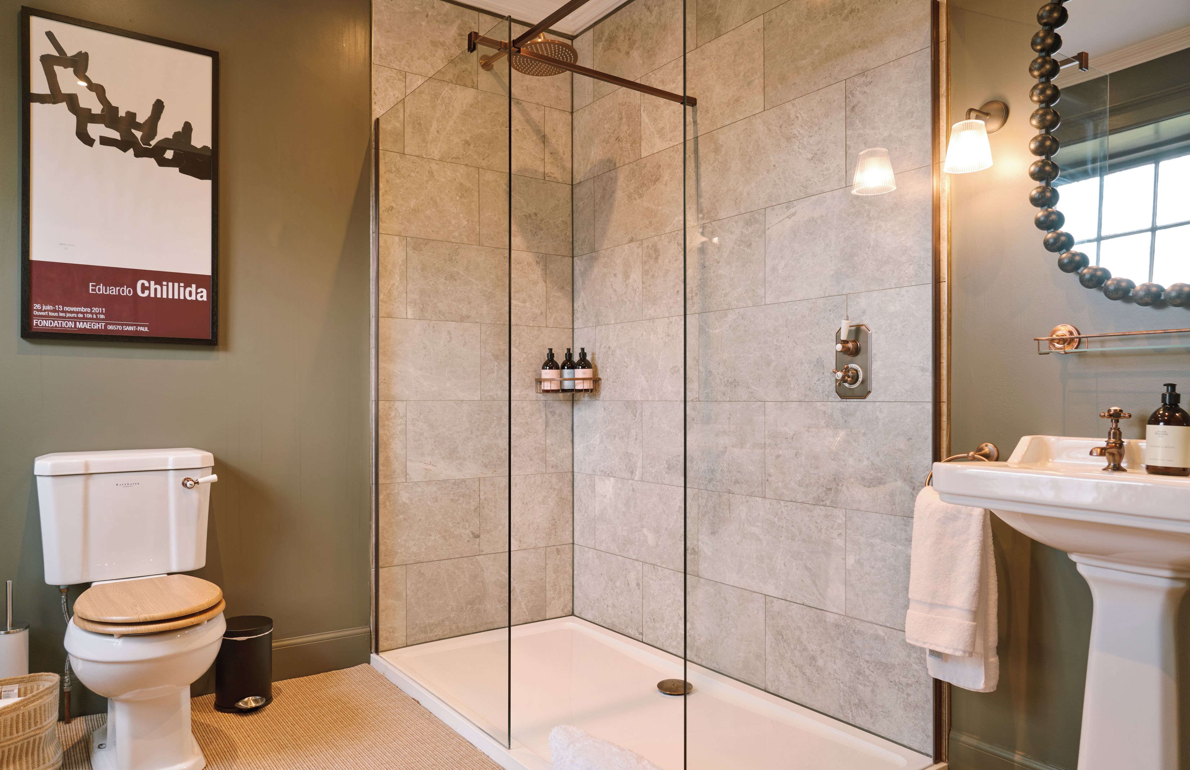 A modern bathroom with a glass-enclosed shower, a white toilet, and a sink with a mirror.