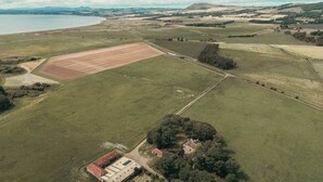 An aerial view of a rural landscape with fields, a large open area, and a building with a red roof.