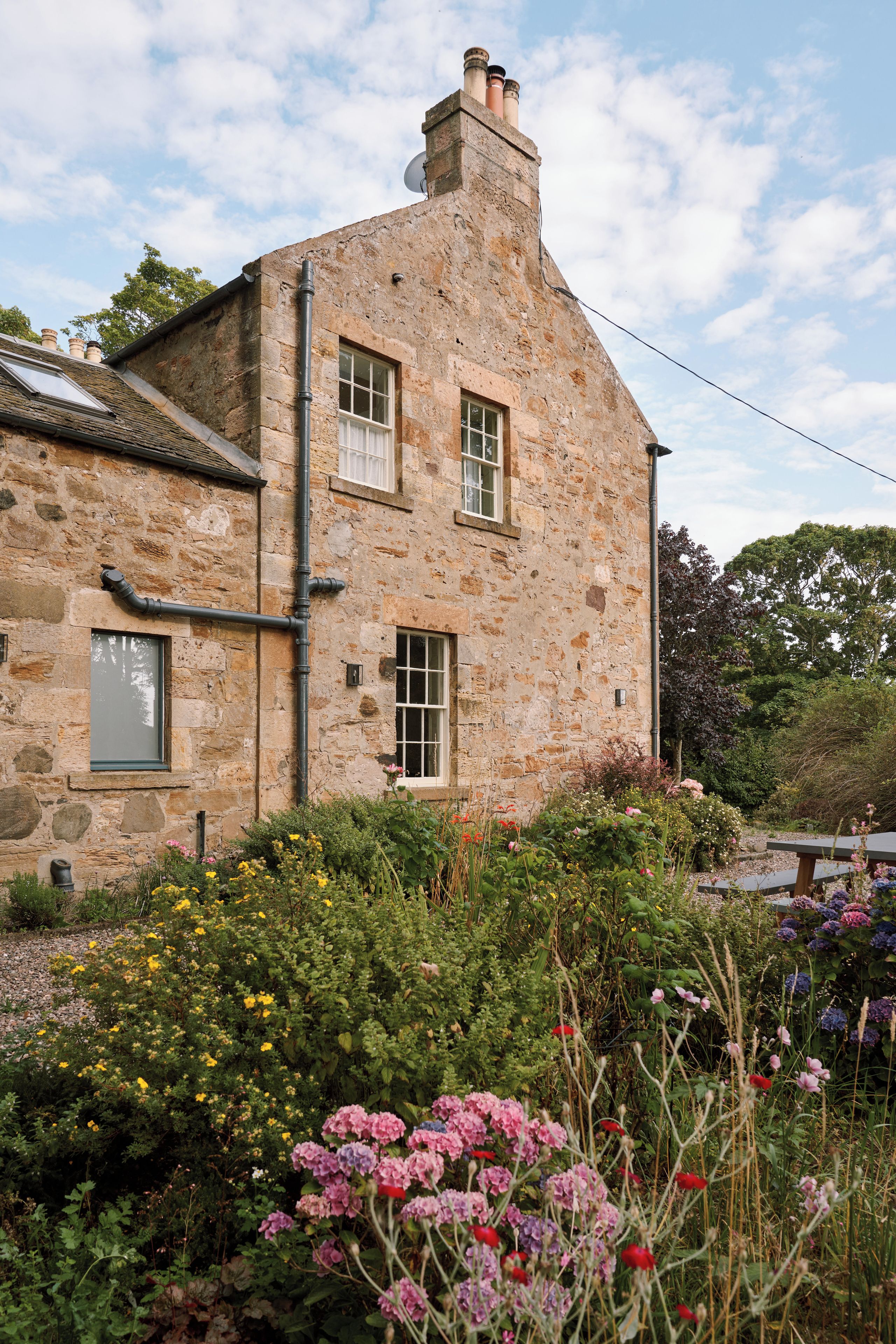 A stone building with two windows and a chimney.