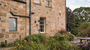 A stone building with two windows and a chimney.