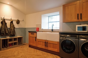 Una cucina moderna con mobili in legno, lavatrice integrata e una finestra che offre luce naturale.