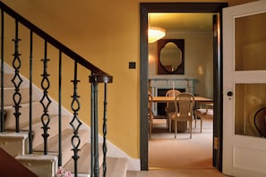Una scala con balaustre nere decorate conduce a una stanza con un tavolo da pranzo e sedie.