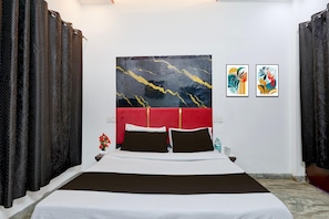 A hotel room with a large bed, a red headboard, two wall-mounted artworks, and dark curtains. - Hotel O Dariya Railway Station (Chandigarh)