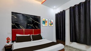 Een hotelkamer met een groot bed, een rode hoofdbord, een marmeren vloer en kunstwerken aan de muren.