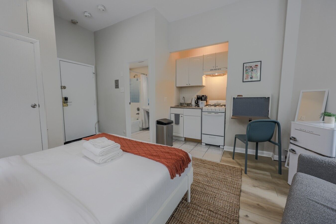Une chambre d’hôtel comprenant un lit, un bureau, une chaise, un coin cuisine et une salle de bain.
