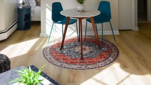 A dining area with a round table, two blue chairs, a potted plant, and a patterned rug. - Comfy Back Bay Alcove Studio Apt (Boston)