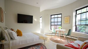 A modern bedroom with a bed, a small table, chairs, and a TV.