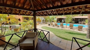 A covered outdoor area with lounge chairs, a pool, and a well-maintained lawn. - POUSADA PORTO MAR (Ipojuca)