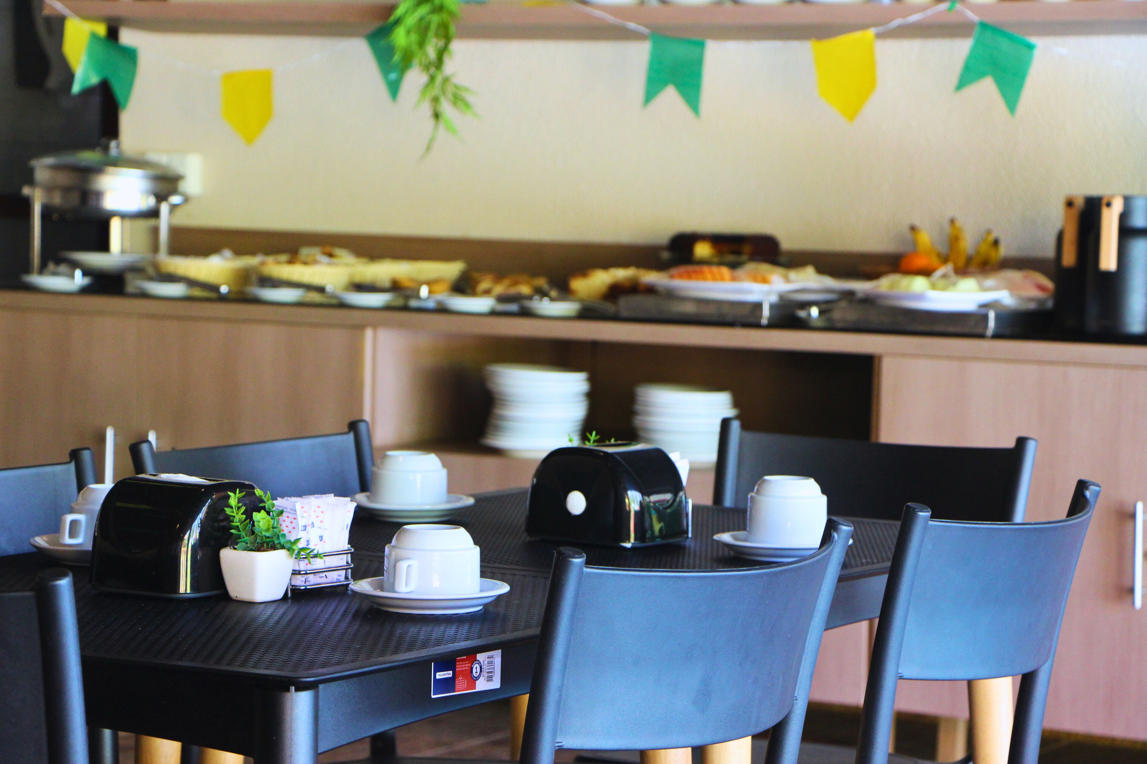 A dining area with a buffet setup, including plates, cups, and a coffee machine.