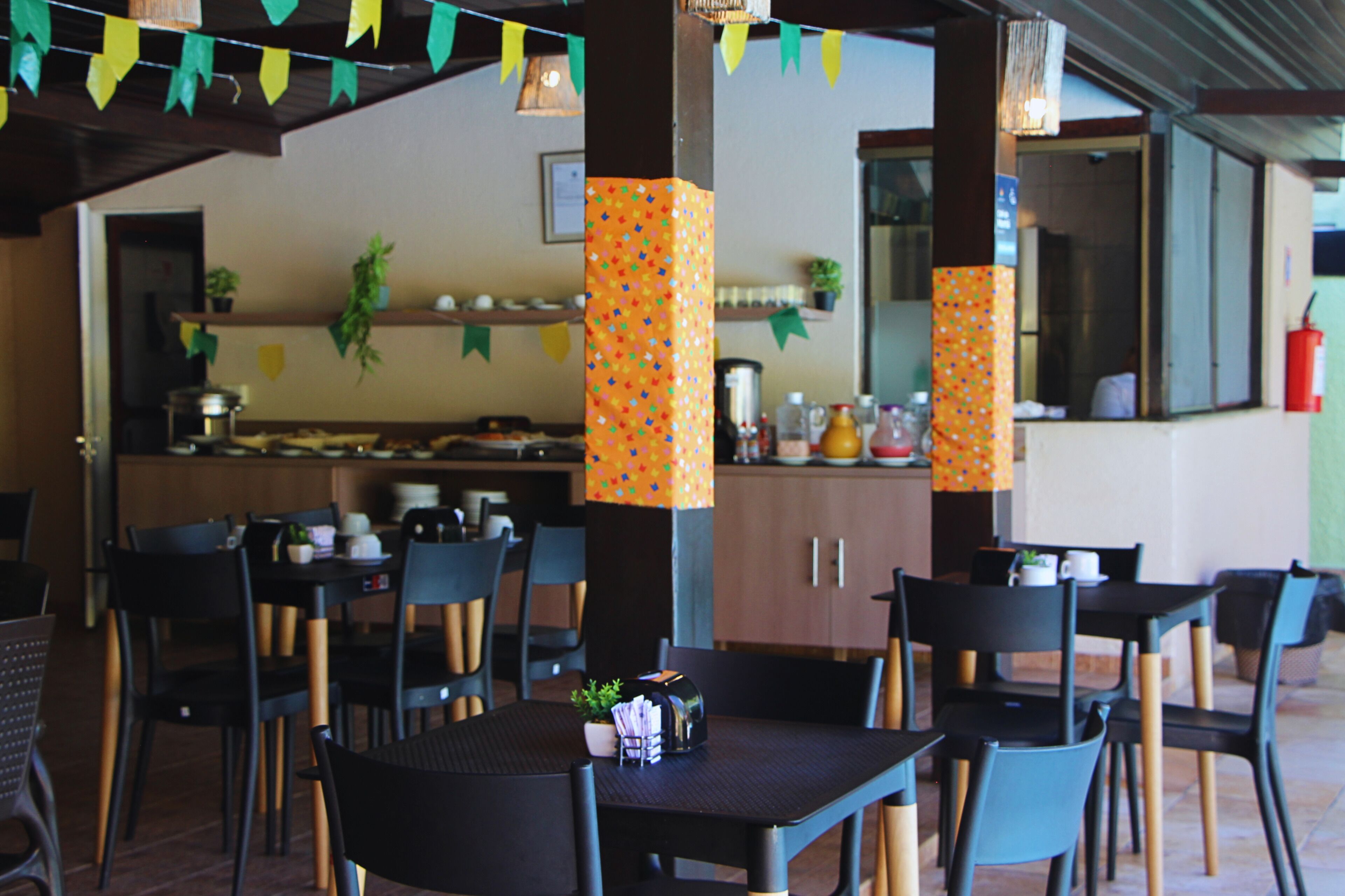 Een restaurant met terras, een keuken op de achtergrond en kleurrijke decoraties.