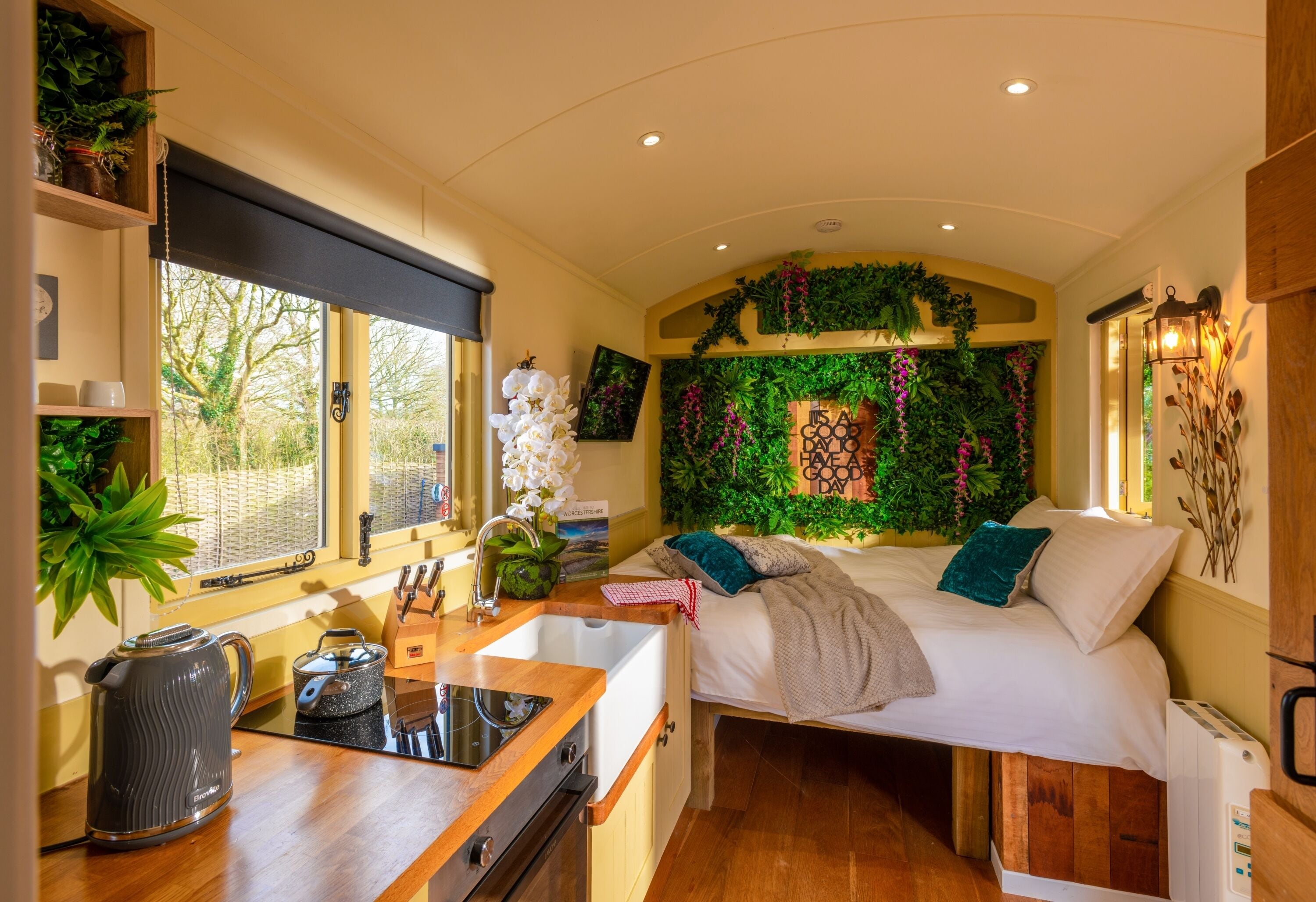 A compact bedroom with a bed, bedside table, and a built-in sink.