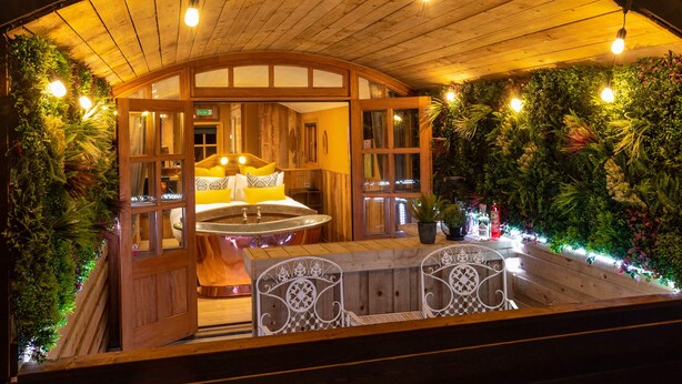 Un'accogliente area esterna con una panca di legno e un tavolo, immersa nel verde e riparata da un pergolato in legno.