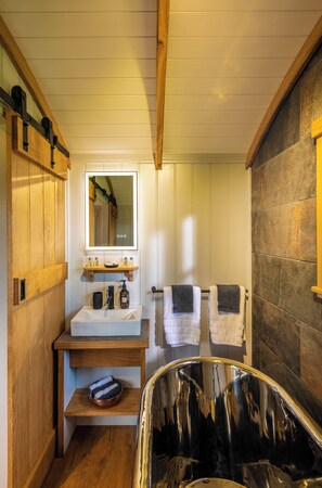 A bathroom with a wooden vanity, a mirror, a sink, and a bathtub.