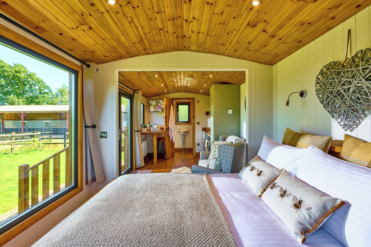 A spacious bedroom with a large bed, a view of the outdoors, and a wooden ceiling.