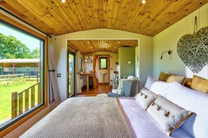 A spacious bedroom with a large bed, a view of the outdoors, and a wooden ceiling. - Ockeridge Rural Retreats (Worcester)