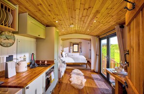A cozy bedroom with a wooden ceiling, a large bed, and a view of the outdoors. - Ockeridge Rural Retreats (Worcester)