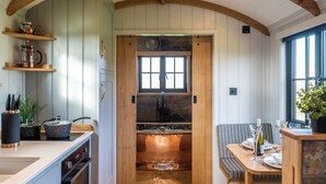 Una cucina con travi in legno, un camino in pietra e un'area pranzo con una panca.