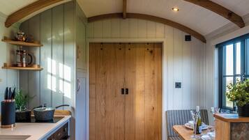 A kitchen with wooden beams, a central door, and a dining area with a table and chairs.