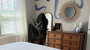 A bedroom with a large bed, a dresser, a mirror, and a wall with an octopus mural. - Organic Modern Home, Close to the Beach & Downtown. Community Pool & gym (St. Augustine)
