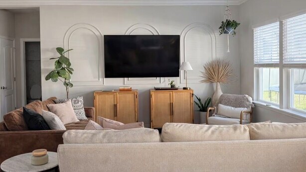 A living room with a sofa, a television, wooden cabinets, and a plant. - Organic Modern Home, Close to the Beach & Downtown. Community Pool & gym (St. Augustine)