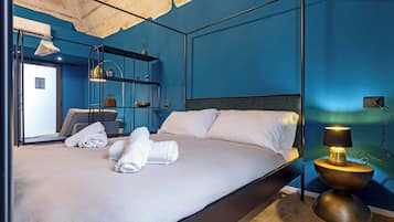 Una camera d'albergo moderna con un letto grande, un comodino con una lampada, un armadio e uno specchio.