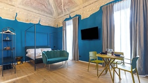 Una habitación con cama, una silla colgante, una mesa de comedor con sillas, un televisor montado en la pared y un techo con frescos.