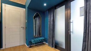 Una habitación con puerta blanca, un banco, un espejo y una puerta corredera de vidrio.