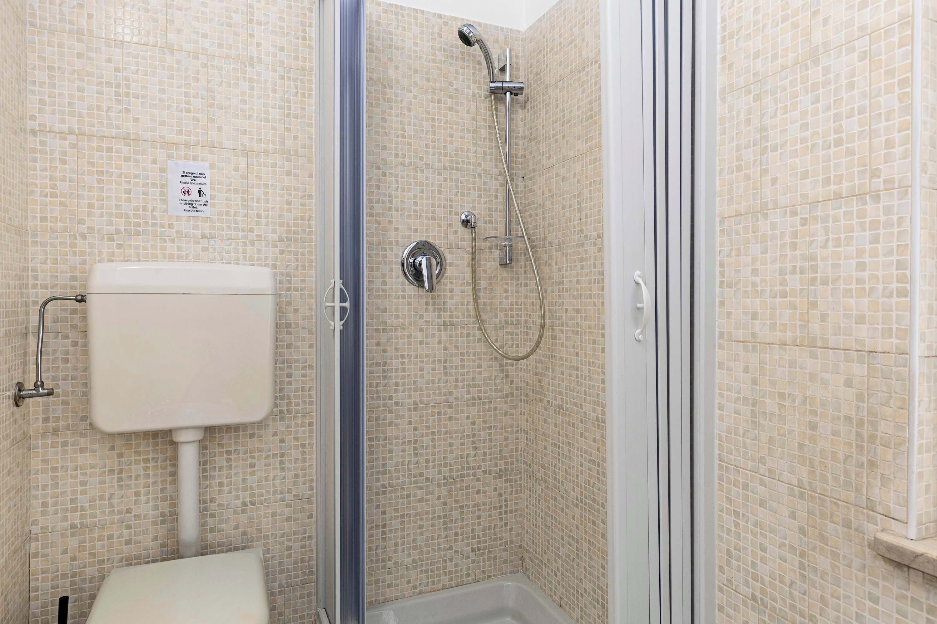 Ein Badezimmer mit Toilette, Dusche und gefliesten Wänden.