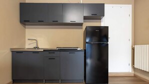 Eine moderne Küche mit dunklen Schränken, einem Edelstahlkühlschrank und einer weißen Tür.