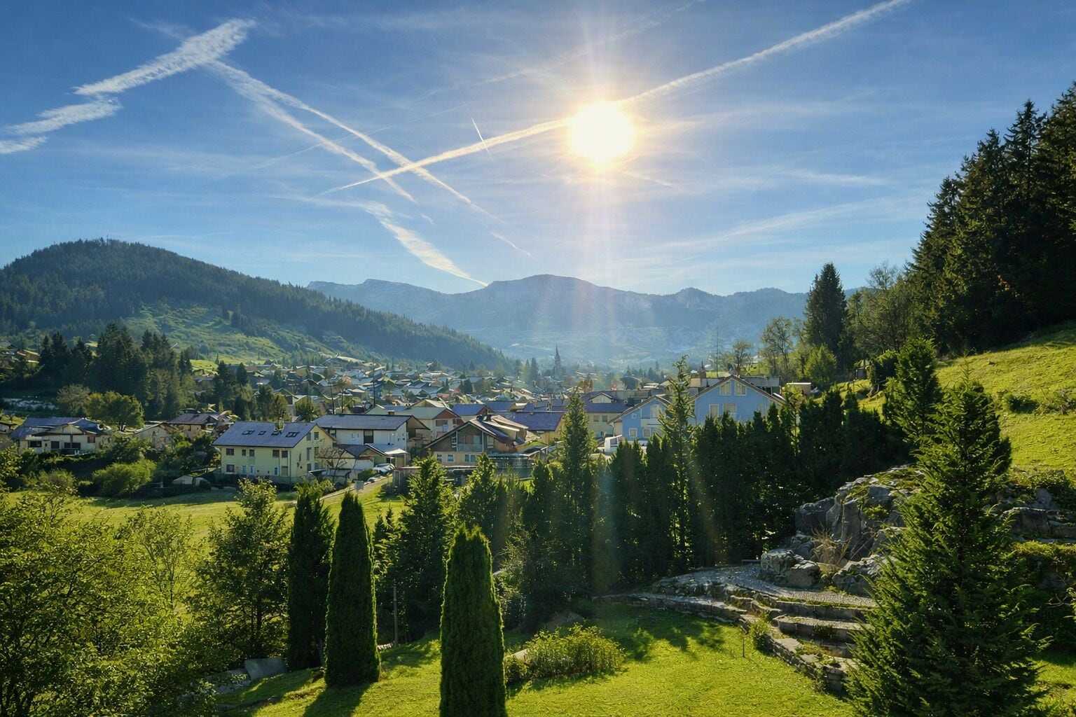 Eine Stadt mit Häusern, einem Fluss und Bergen im Hintergrund.