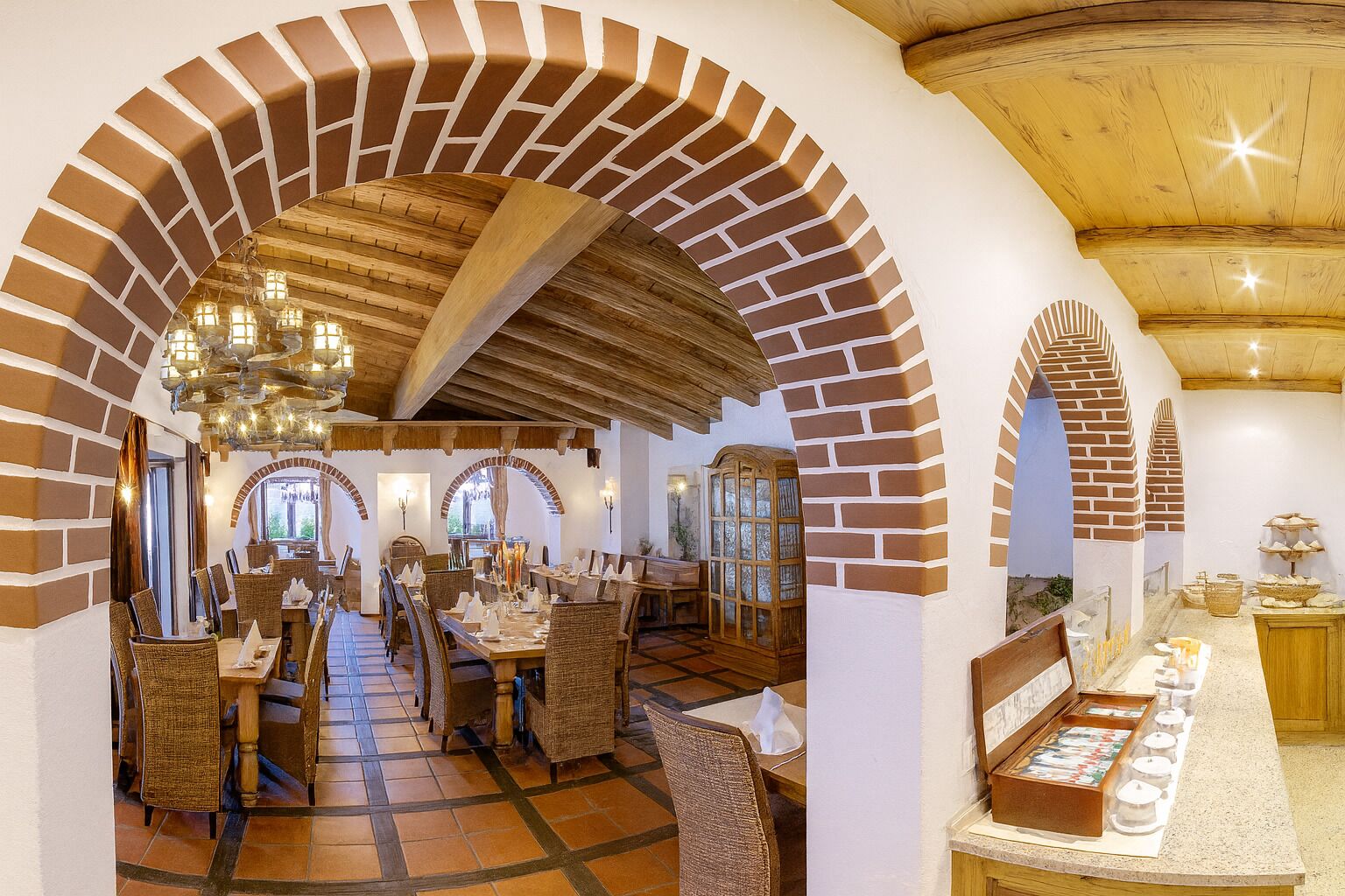 A restaurant with brick arches, wooden ceiling beams, and wicker furniture.
