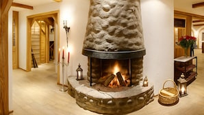 A stone fireplace with a fire, a candelabra, and a lantern. - ALPRESORT Hubertushof (Oberstaufen)