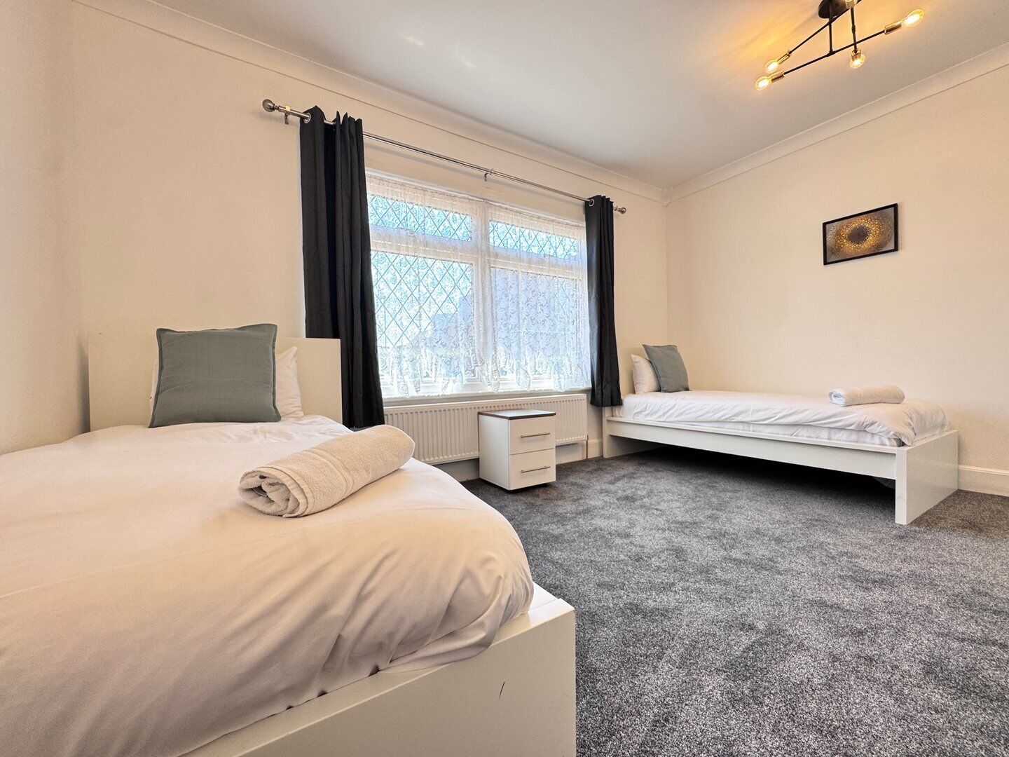 Une chambre avec deux lits, un radiateur, un bureau et une fenêtre avec des rideaux.