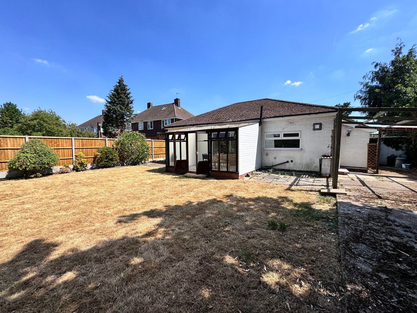 A backyard with a covered patio, a fenced area, and a small shed.