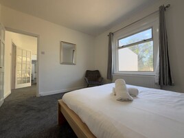 Un dormitorio con una cama grande, una silla, un espejo y una ventana con cortinas.