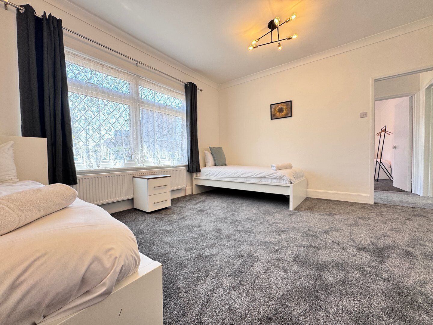 A bedroom with a large window, a bed, a desk, and a radiator.