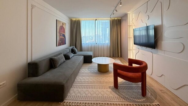 Een moderne woonkamer met een bank, een rond bijzettafeltje en een rode fauteuil.