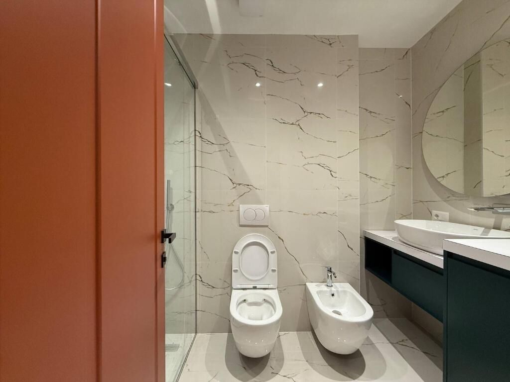 Une salle de bain moderne équipée de toilettes, d’un bidet et d’un grand miroir.
