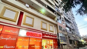 A building with a storefront labeled "CONAD" featuring large windows and a red awning.